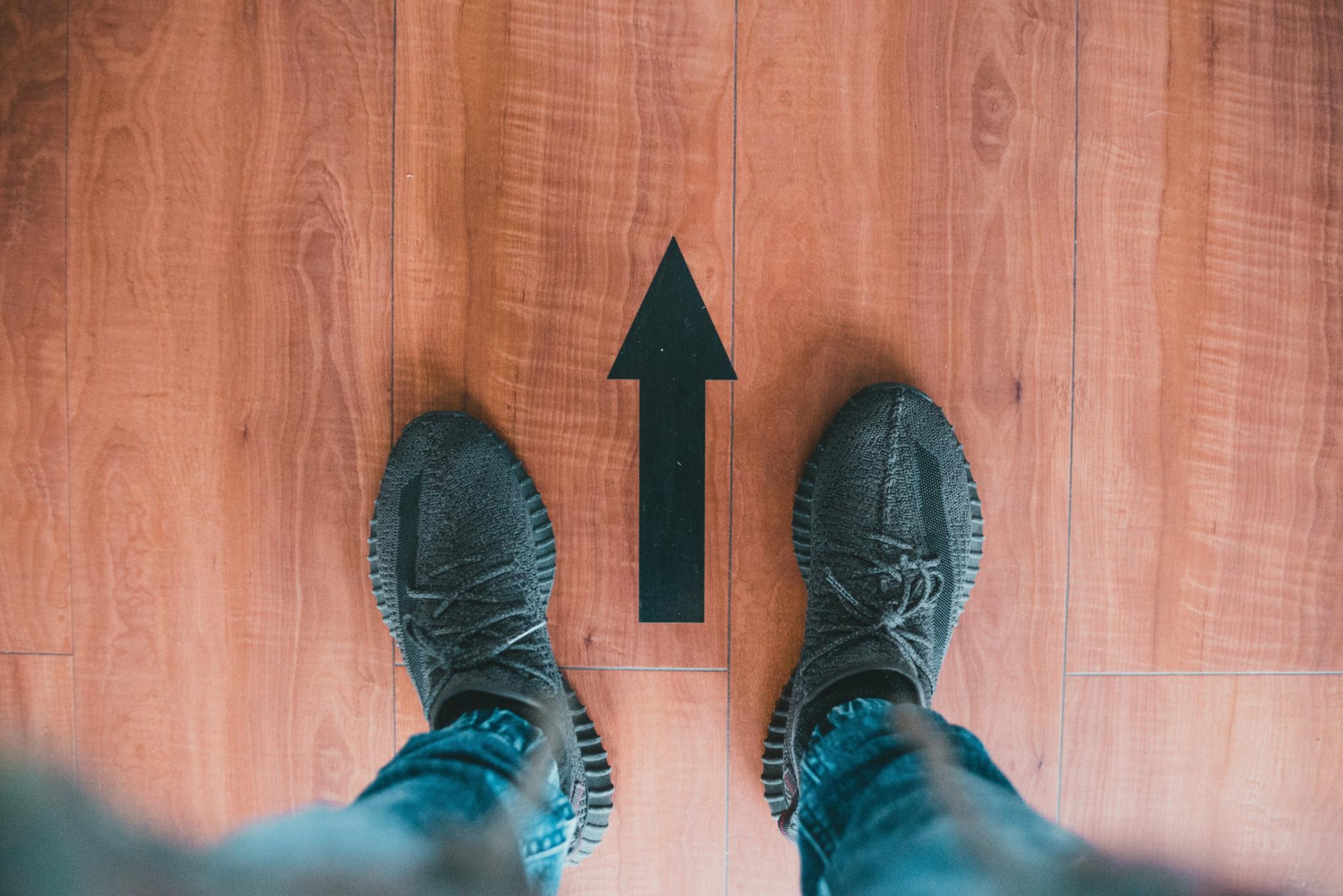 Person steht an einem Richtungspfeil