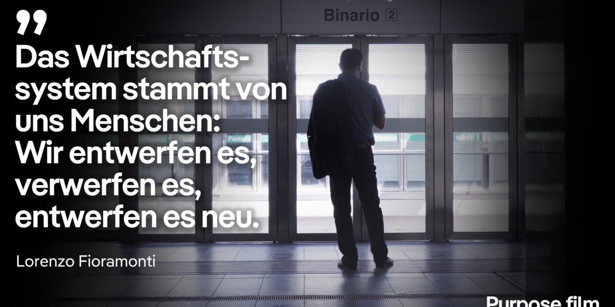 Lorenzo Fioramonti steht in einem gläsernen Bereich vor dem Einstieg in eine U-Bahn, darauf sein Zitat: 'Das Wirtschaftssystem stammt von uns Menschen: Wir entwerfen es, verwerfen es, entwerfen es neu.'