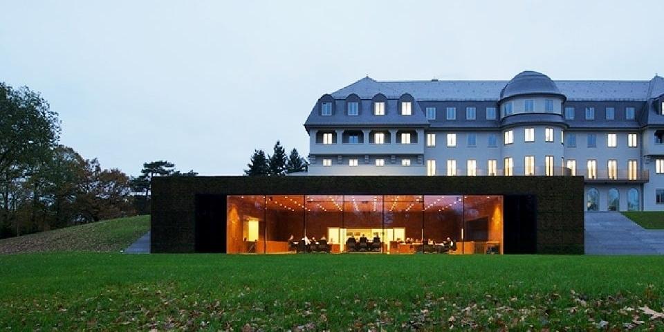 Außenansicht des Parlamentsgebäudes, ein ehemaliges Sanatorium aus dem Jahr 1915 mit einem vorgebauten Plenarsaal mit Glasfront.