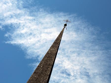 Kirchturm ragt vor dem Himmel auf, in der Perspektive ist er nach rechts geneigt.