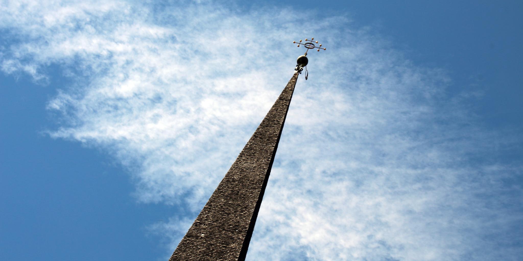 Kirchturm ragt vor dem Himmel auf, in der Perspektive ist er nach rechts geneigt.