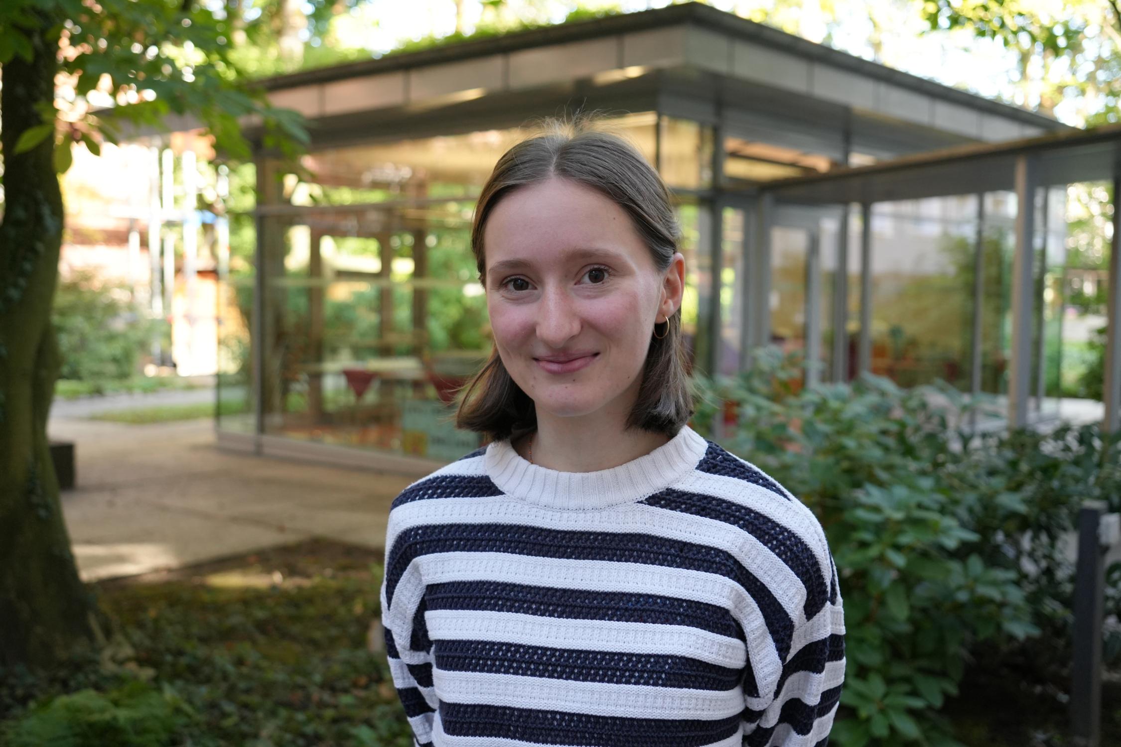 Eine junge Frau vor dem Gartenpavillon der Akademie.