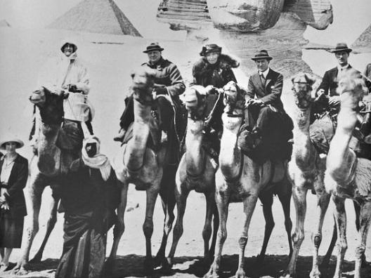 Ein Foto aus dem Jahr 1921. Personen reiten auf Kamelen, aufgenommen vor der Statue der Sphinx in Ägypten: das Ehepaar Churchill, Gertrude Bell und T. E. Lawrence.