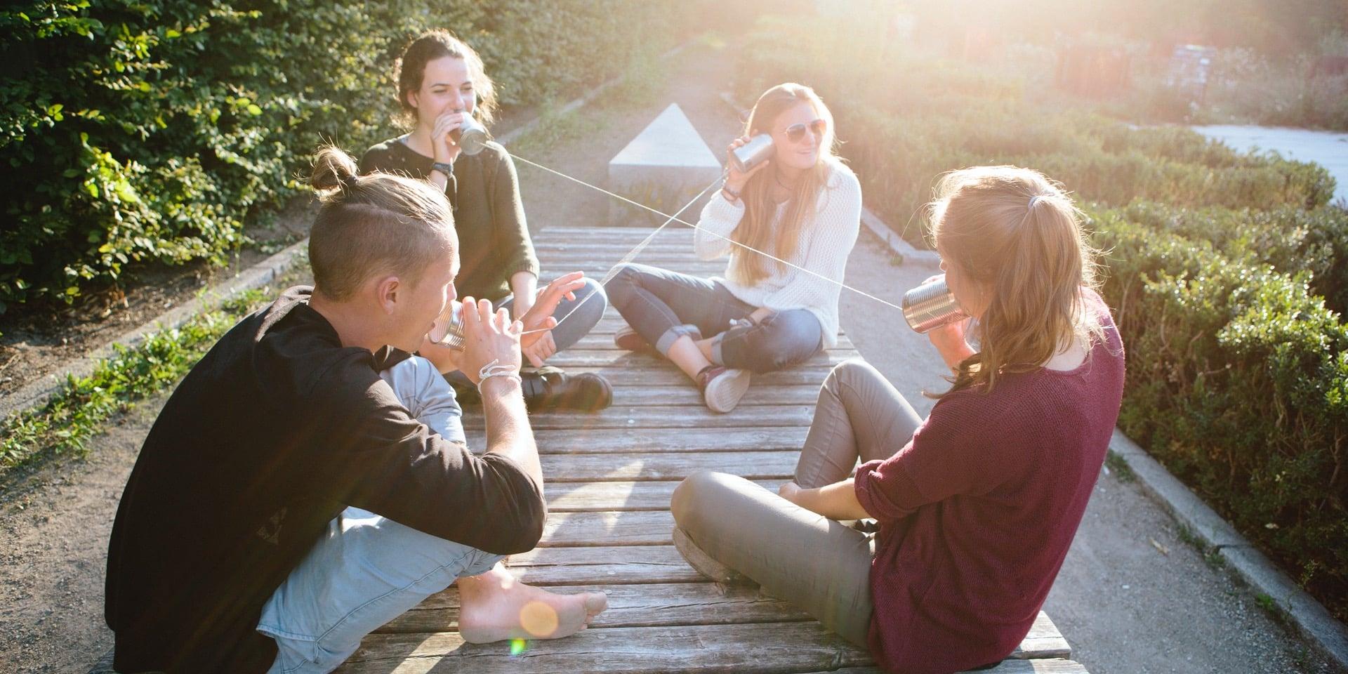 Junge Menschen sitzen in einer Gruppe auf dem Boden und unterhalten sich.