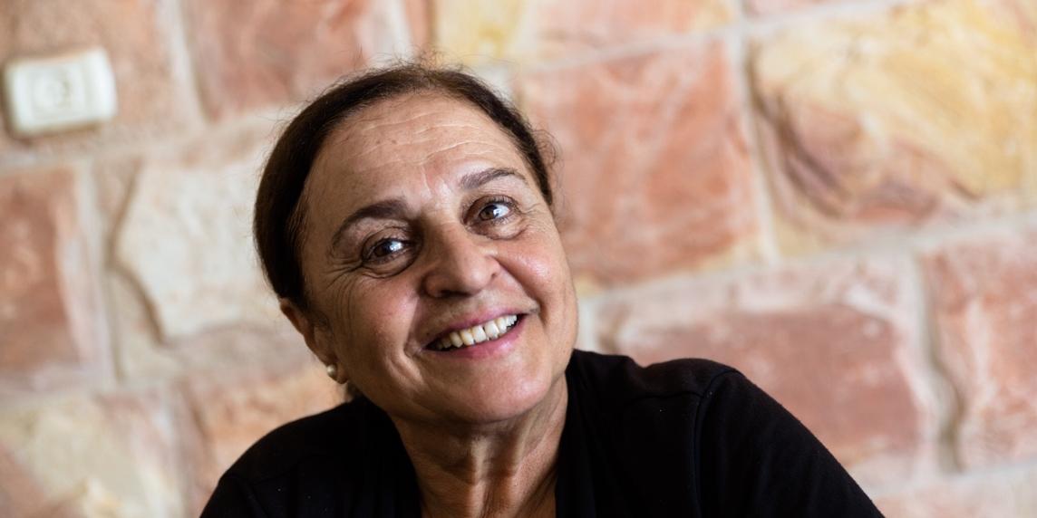 Porträt einer Frau, der palästinensischen Autorin Sumaya Farhat-Naser, vor einer Mauer