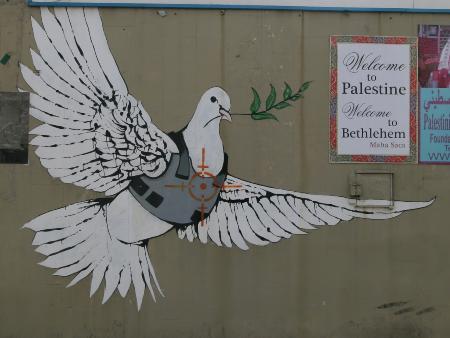 Wandgemälde: eine weiße Taube in einer kugelsicheren Weste mit einem Olivenzweig, gemalt auf einer Souvenirladenwand.