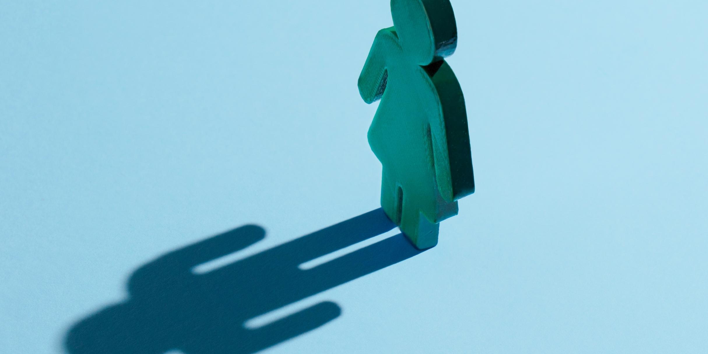 Eine Figur einer Frau, in ihren symbolischen Konturen, die einen Schatten eines Mannes wirft.