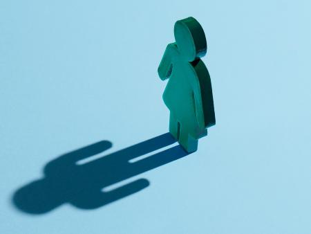 Eine Figur einer Frau, in ihren symbolischen Konturen, die einen Schatten eines Mannes wirft.