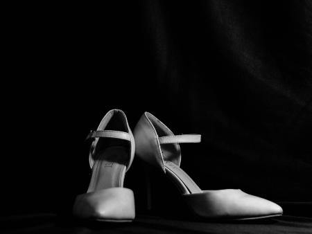 Ein Paar Frauenschuhe, hohe Pumps, vor schwarzem Hintergrund.