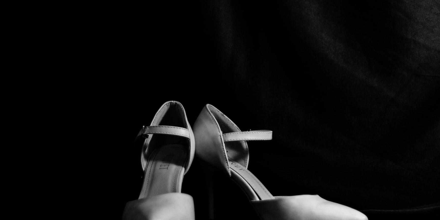 Ein Paar Frauenschuhe, hohe Pumps, vor schwarzem Hintergrund.