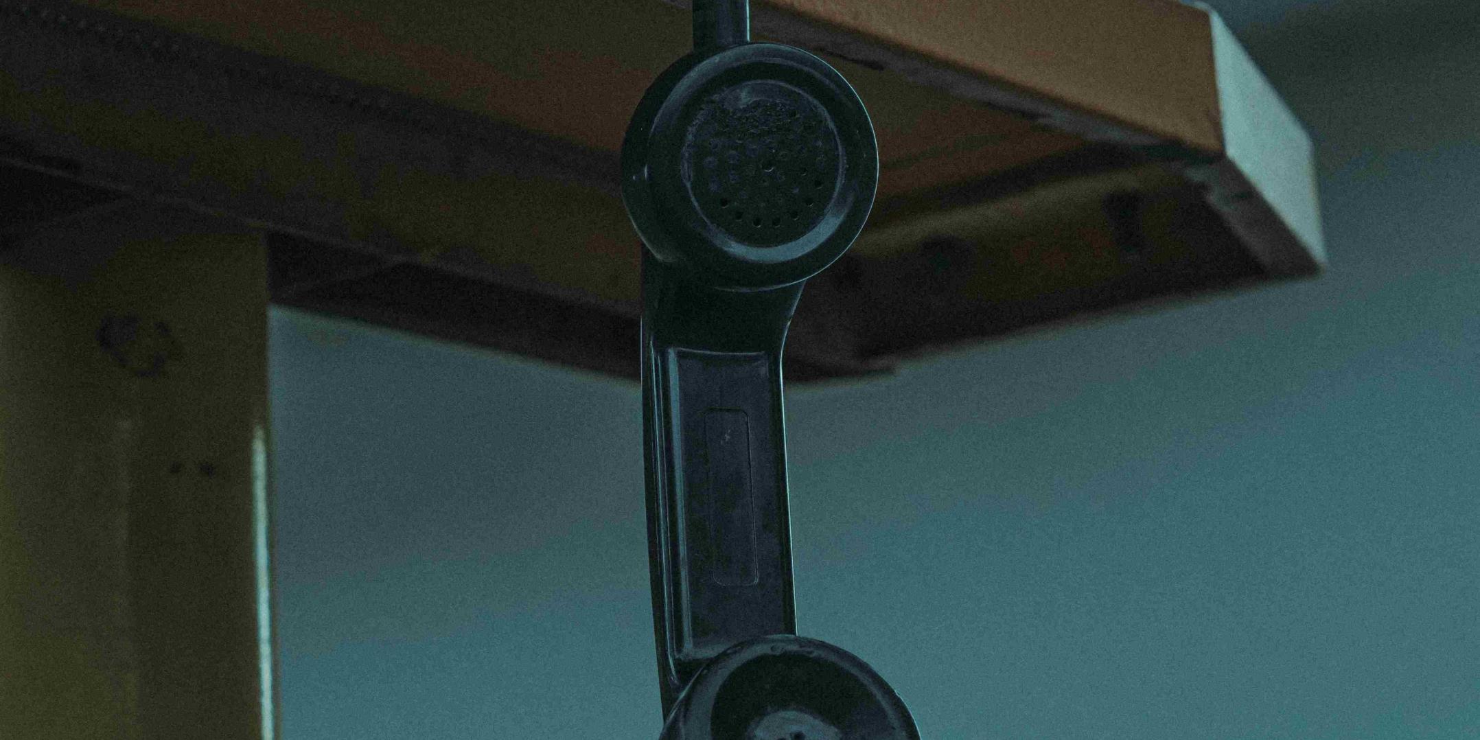 Hörer eines alten Telefons hängt von einem Tisch herunter.