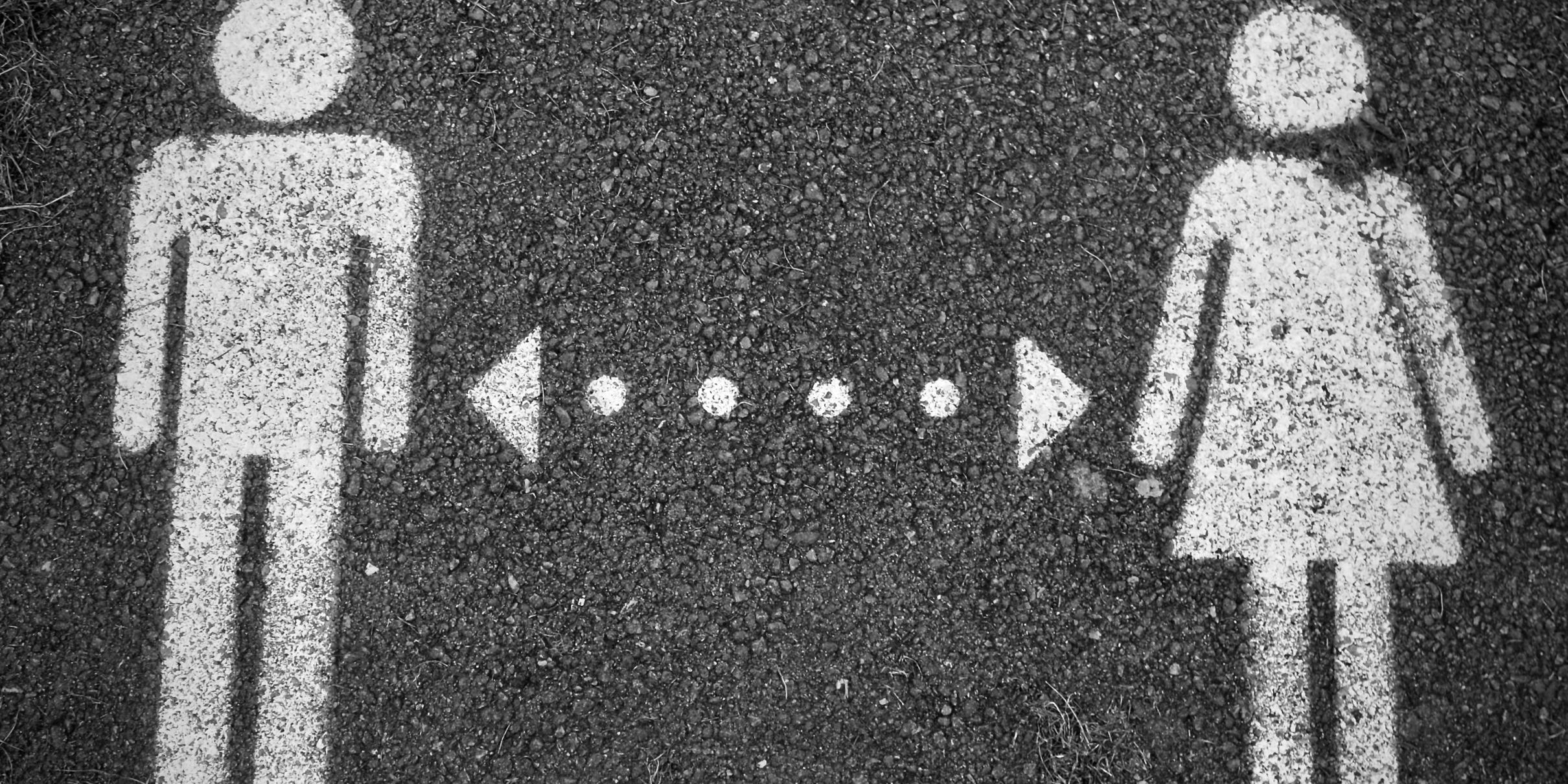 Symbol eines Mannes (links) und einer Frau (rechts), mit Kreide gemalt, dazwischen eine gepunktete Linie mit jeweils einem Pfeil nach rechts und links.