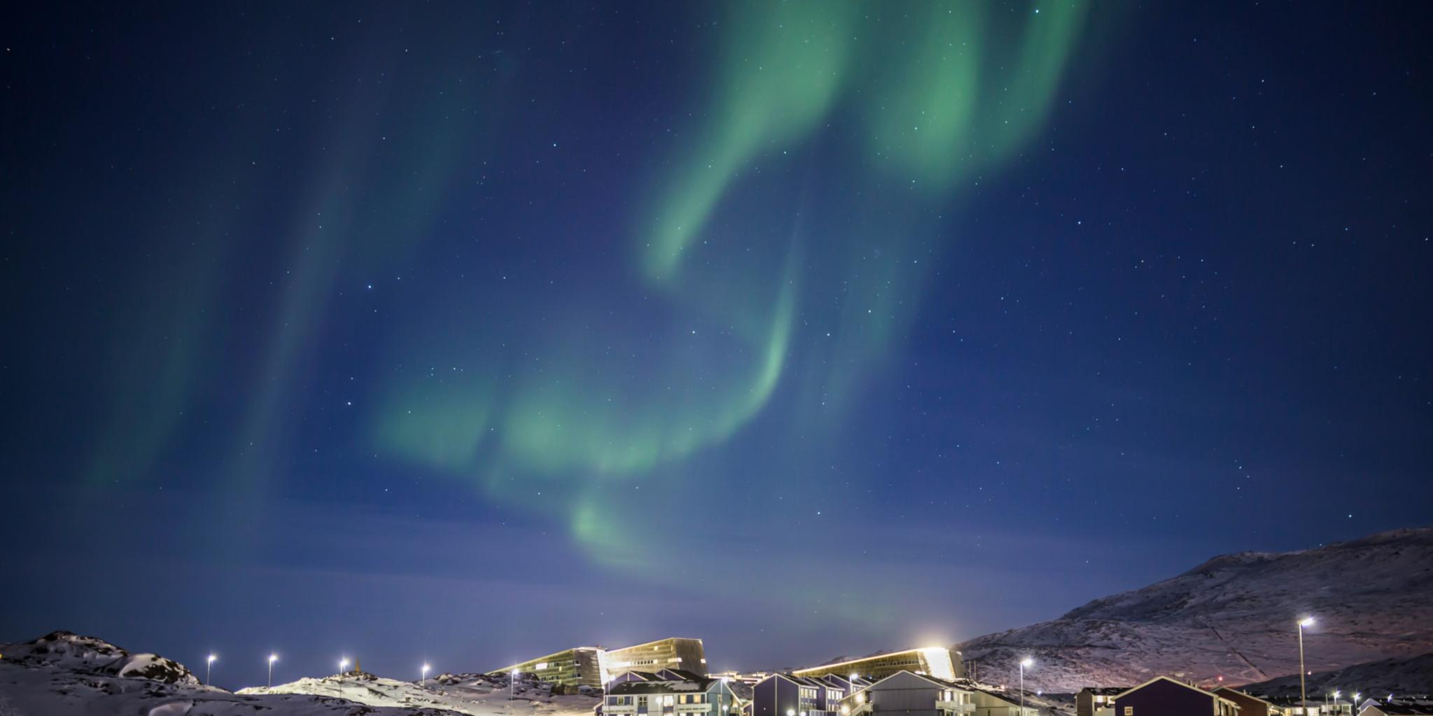 Polarlicht über Häusern auf Grönland